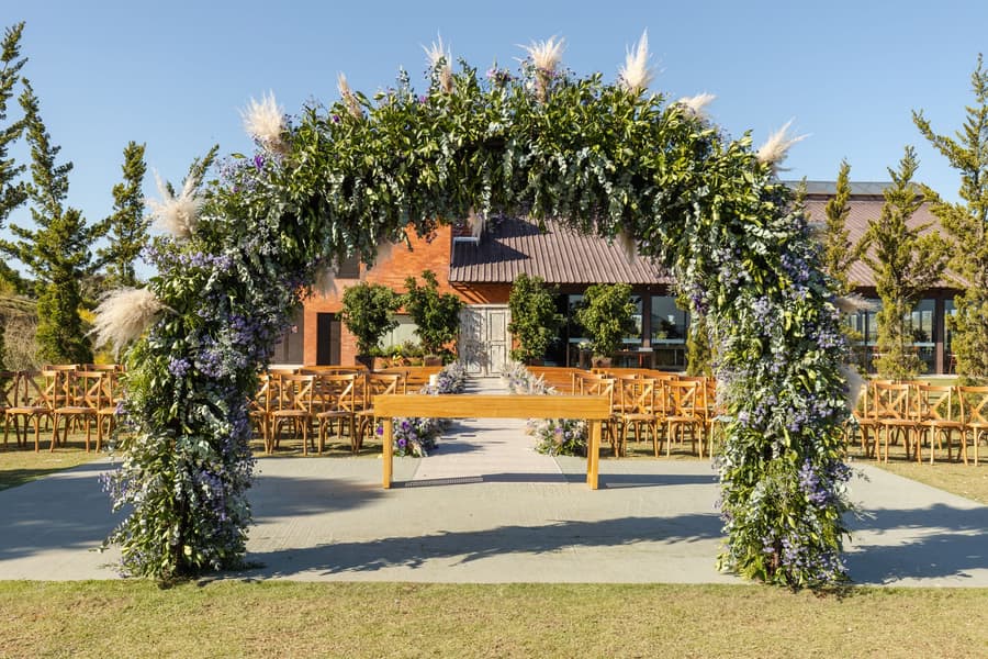 The ceremony arch of greenery and pampas, a timber altar table beneath it