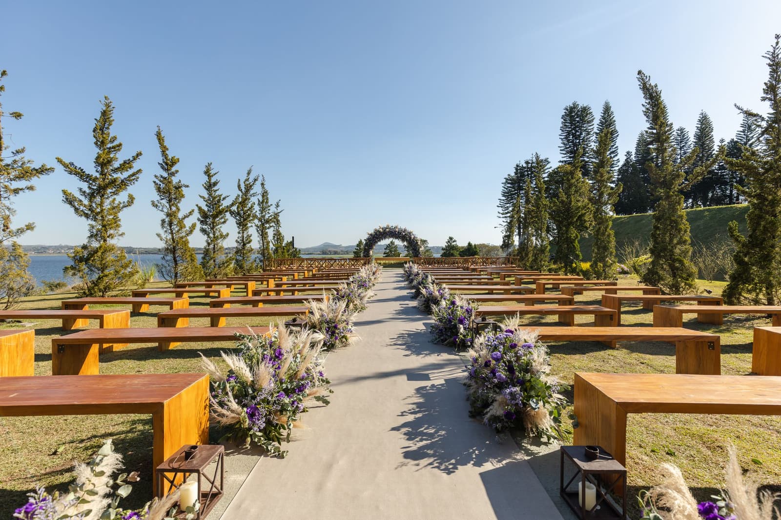 The whole ceremony field: benches, the aisle, the arch, the lake beyond